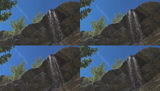 32、春天的蓝天绿树映衬下，银色的喷射山瀑布高清在线视频素材下载