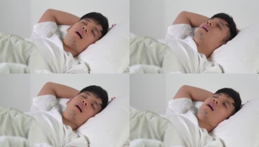 年轻的亚洲男人在床上睡觉时打鼾。高清在线视频素材下载