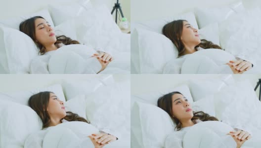 亚洲美丽的舒适女孩在睡衣从卧室起床。迷人的年轻女子躺在床上感到幸福舒适的枕头和毯子享受清晨醒来后的房间在家里高清在线视频素材下载