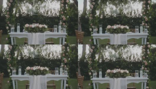 令人惊叹的婚礼布置在花园，白色桌布和木制椅子的桌子。美丽的节日气氛。花园里到处都是粉红色和白色的玫瑰。高清在线视频素材下载