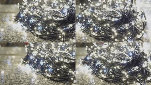 许多发光的LED灯泡在室内。这些是用来做圣诞装饰的。灯泡的电线放在地板上。卡车从右向左射击。主题在右边。低角度。高清在线视频素材下载