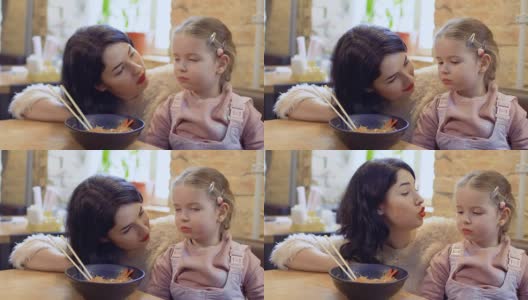 一名年轻女子劝她的小女儿尝尝韩国美味面条高清在线视频素材下载