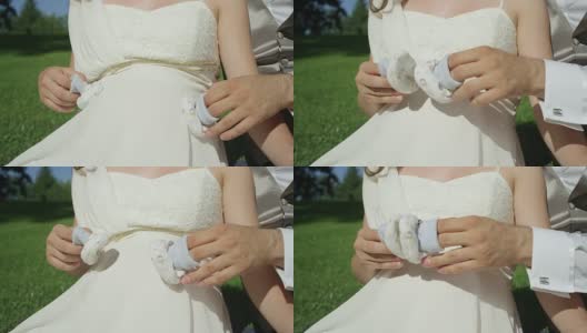 慢镜头:一对认不出来的新婚夫妇用手指玩婴儿鞋。高清在线视频素材下载