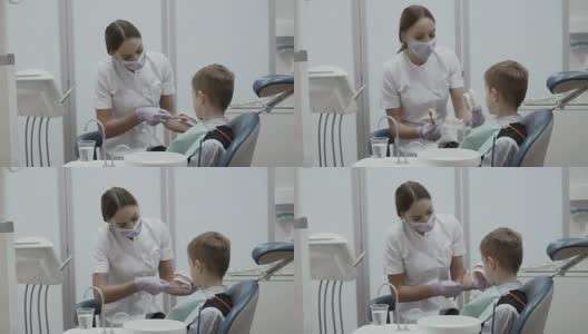牙医在一个牙齿模型上教一个小男孩如何用牙刷刷牙高清在线视频素材下载