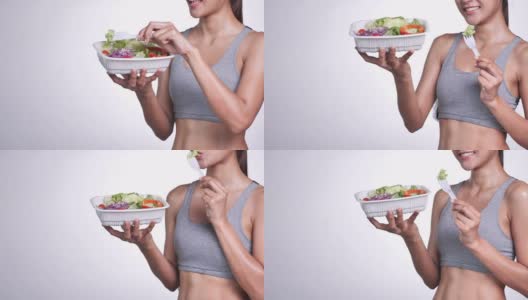 年轻的亚洲女人在一个白色的背景吃沙拉，水果和蔬菜美味的饮食。高清在线视频素材下载