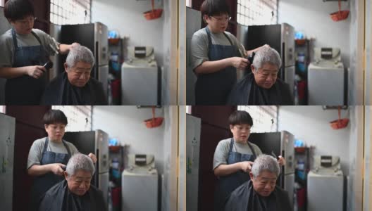 由于旅行禁令，一位亚洲华人中年妇女正在厨房里为她的父亲修剪头发高清在线视频素材下载