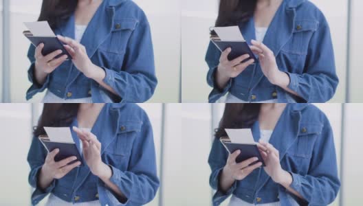 一名身穿蓝色夹克的女子在终点站用手机持有护照和机票高清在线视频素材下载