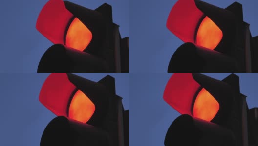 一个以傍晚天空为背景的红绿灯的特写。红色禁行交通灯。红绿灯镜头高清在线视频素材下载