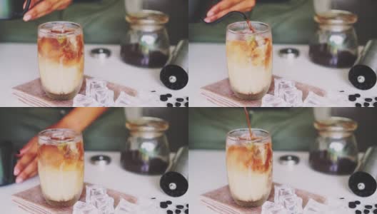 一个咖啡师的手倒牛奶使冰咖啡在桌子上。高清在线视频素材下载