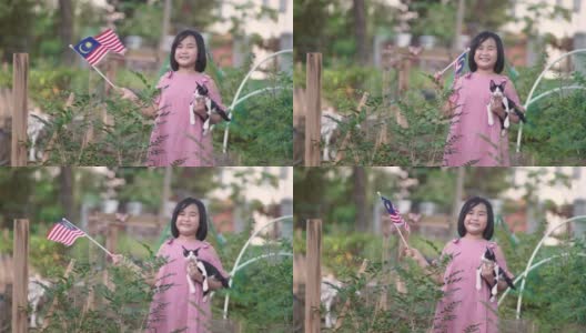 亚洲中国女孩和她的宠物猫在家里的农场里挥舞国旗高清在线视频素材下载