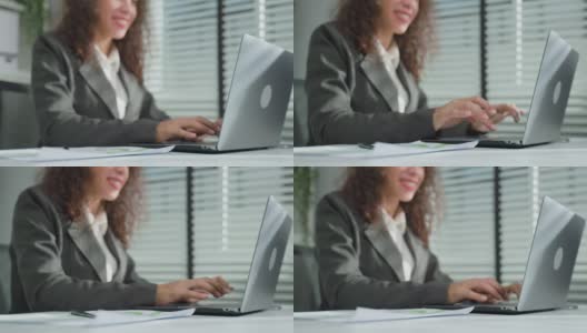 拉丁美洲美丽的商业女人微笑着在办公室工作。漂亮的职业女性员工穿着正式的服装坐在工作场所的桌子上，使用笔记本电脑和键盘打字。高清在线视频素材下载