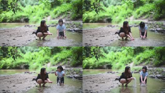 一位亚裔中国妇女和她的女儿在河边玩水花高清在线视频素材下载