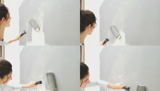 年轻女子正在用油漆滚筒刷墙高清在线视频素材下载