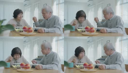 迷人的年轻老年亚洲公民夫妇愉快地坐着聊天，吃汤的健康营养早餐餐在餐桌上的早上在老亚洲人的观念日常生活方式。高清在线视频素材下载