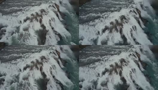 鸟瞰悬崖上汹涌的水流。一架直升机飞过冰岛的大瀑布高清在线视频素材下载