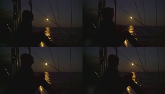 4K女人在帆船上放松，背景是满月照在海上高清在线视频素材下载