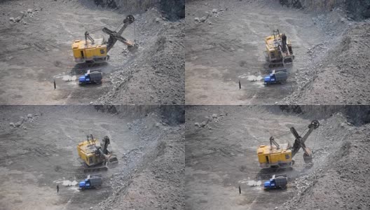 旁边站着一个正在往卡车上装石头的黄色挖掘机高清在线视频素材下载
