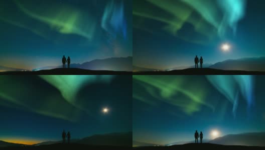 这对夫妇站在山上，映衬着北极光的天空。时间流逝高清在线视频素材下载