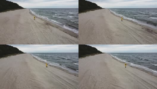 一名女子在狂风暴雨的海滩上奔跑，被无人机拍摄下来高清在线视频素材下载