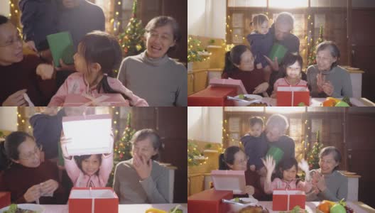 多代家庭坐着吃健康食品，同时打开圣诞礼物礼盒在家高清在线视频素材下载