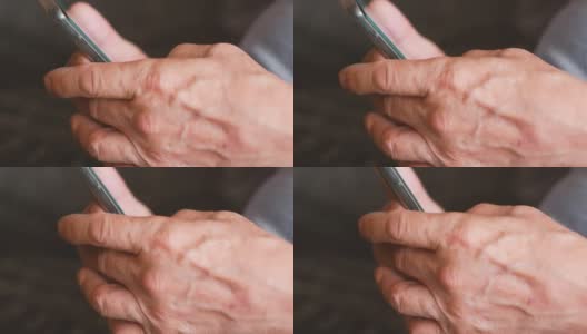 老年人学习使用电子产品的主题。特写一位老人的皱纹的手拿着智能手机，试图打开一个互联网页面。选择性聚焦，浅景深高清在线视频素材下载