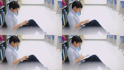 亚洲男大学生在图书馆地板上看书做研究。高清在线视频素材下载