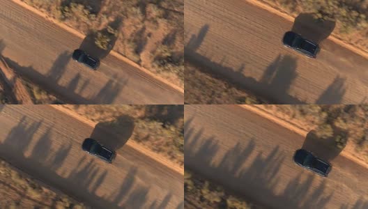 空中特写:飞过黑色越野车行驶在尘土飞扬的沙漠道路上高清在线视频素材下载