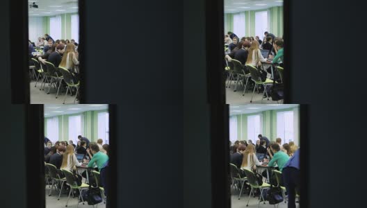 一大群人坐在一个明亮的教室里一起工作。年轻的经济学家坐在桌旁讨论实践，等待讲座的开始高清在线视频素材下载