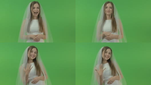 年轻的白人女孩穿着新娘礼服，在绿色的背景上。她手指上戴着一枚订婚戒指高清在线视频素材下载