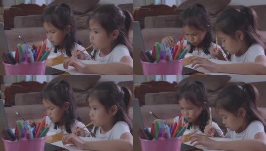 两个亚洲女孩用笔记本一起学习在线技术的慢动作。高清在线视频素材下载