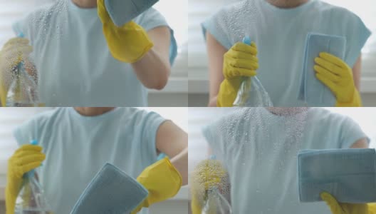 戴黄色手套的女人在洗窗户。她把喷雾瓶里的水洒在玻璃上，用蓝色抹布擦干净。关注前景中的水滴。家务和清洁公司员工的工作概念高清在线视频素材下载