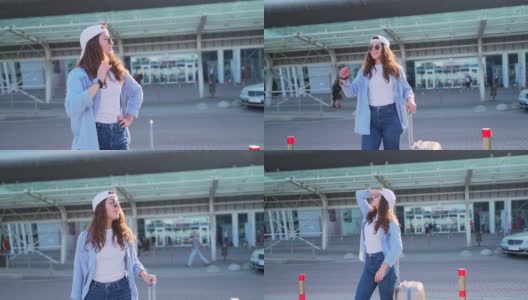 开朗的年轻女子在夏季帽和太阳镜走在机场附近的手提箱高清在线视频素材下载