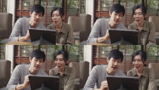 亚洲夫妇在客厅用平板电脑和笔记本电脑办公。高清在线视频素材下载