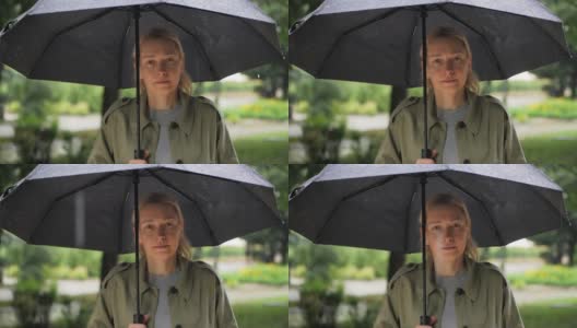 一个女人在雨中站在伞下的脸部特写高清在线视频素材下载