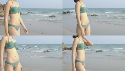 性感的亚洲女人在比基尼沿着海岸走。斯坦尼康慢镜头。夏季，旅游和美丽的概念。高清在线视频素材下载