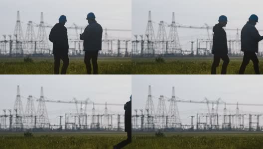 两名工程师戴着安全帽在一个能源站检查期间用智能手机聊天。高清在线视频素材下载