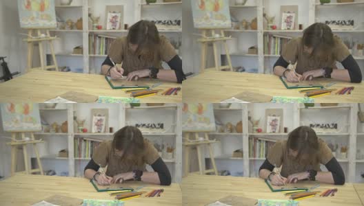 女人正用彩色铅笔坐在书桌前画图画或卡片高清在线视频素材下载