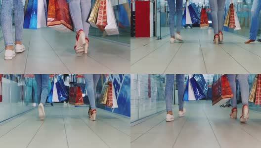 两个女人拿着购物袋在购物中心。后视图，只有腿可见高清在线视频素材下载