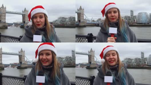 英国伦敦塔桥附近，年轻的女记者戴着圣诞帽，用麦克风讲话高清在线视频素材下载