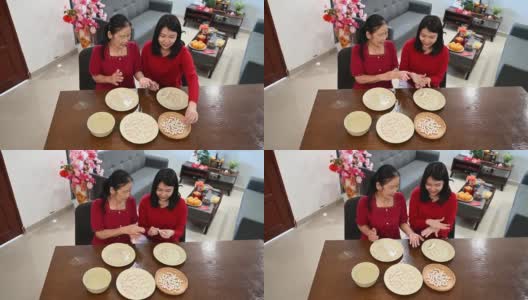 一位亚洲的奶奶和她的孙女正在为庆祝中国新年而准备汤圆高清在线视频素材下载