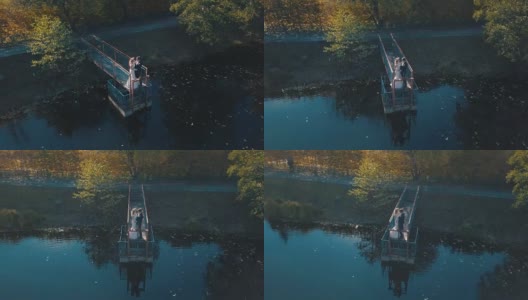 一对年轻的夫妇站在美丽的湖边的一座小桥上高清在线视频素材下载