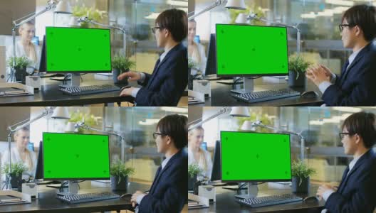 在办公室，商人在模拟绿色屏幕的个人电脑上进行视频通话。他与接受者交谈并积极地做手势。高清在线视频素材下载