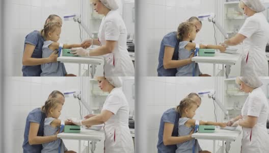 女孩坐在母亲身边，护士为她抽血化验做准备高清在线视频素材下载
