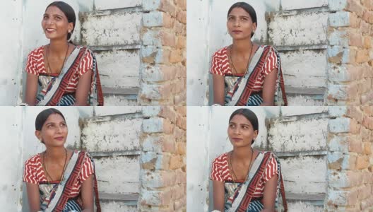 年轻漂亮的女人在家里四处寻找建议，困惑的笑声，微笑，疑惑的微笑坐在台阶上，穿着传统的印度次大陆纱丽连衣裙和衬衫高清在线视频素材下载