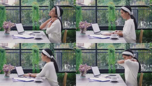 年轻的亚洲女性在家里工作时颈部疼痛，办公室综合症概念高清在线视频素材下载