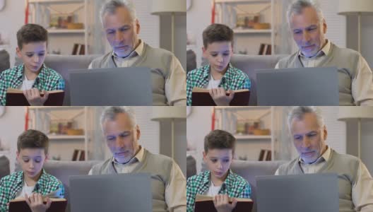 男孩在看书，爷爷在家里用笔记本电脑，不同年龄受教育高清在线视频素材下载