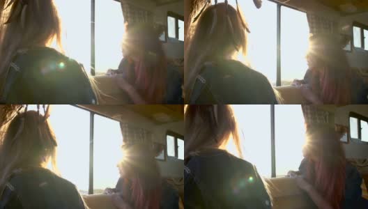 两个女孩在夕阳的余晖中望着汽车拖车的窗外高清在线视频素材下载