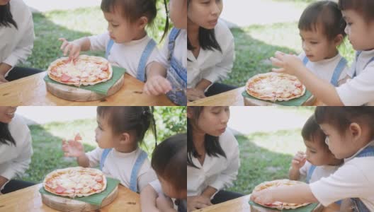 可爱饥饿的小女孩喜欢在后院吃妈妈自制的披萨。小女孩和家人在户外吃午饭。高清在线视频素材下载
