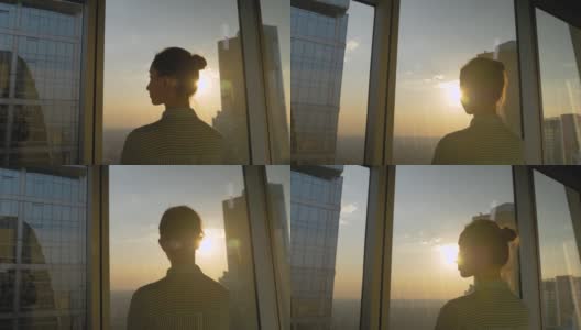 透过摩天大楼的窗户看日落的女人的背影高清在线视频素材下载