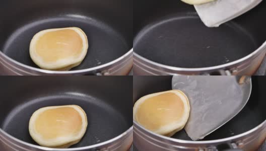 自制的煎饼在不粘锅上做美味的早餐。女性的手用锅铲在热锅上翻动煎饼。高清在线视频素材下载